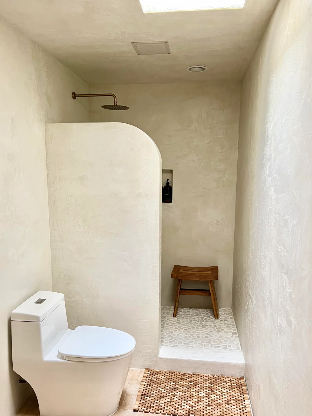 Open-plan microcement bathroom with curved wall